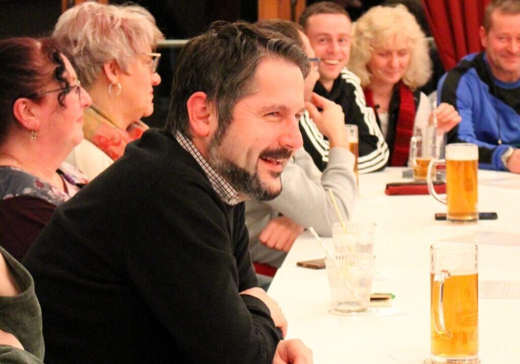 Bürgermeister lachend an Tisch mit mehreren Personen
